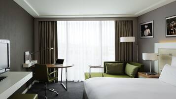 A hotel room with a bed, desk, chair, and a TV.