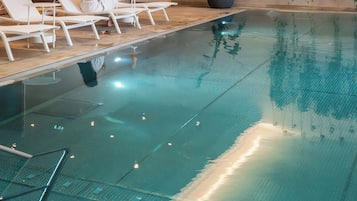 Een binnenzwembad, ligstoelen bij het zwembad