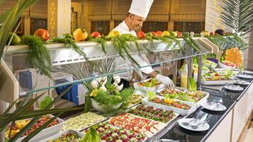 Un buffet proposant une variété de plats, avec un chef cuisinier en arrière-plan.