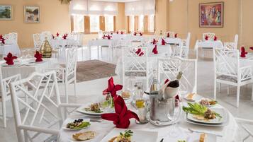A formal dining room with white tables and chairs, arranged for a meal.
