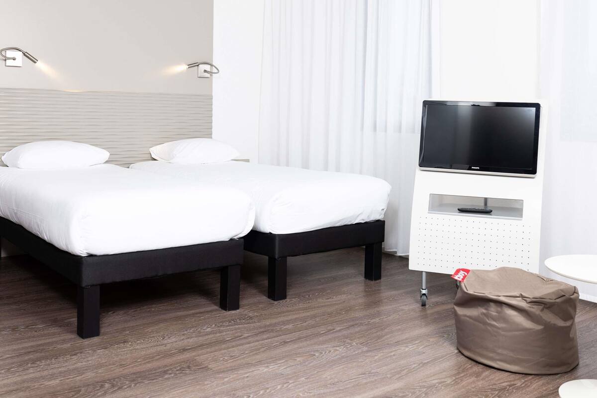Quarto de hotel com cama, televisão e uma pequena mesa.