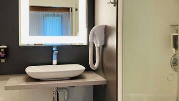 A bathroom with a white sink, a mirror, a hand dryer, and a towel rack.