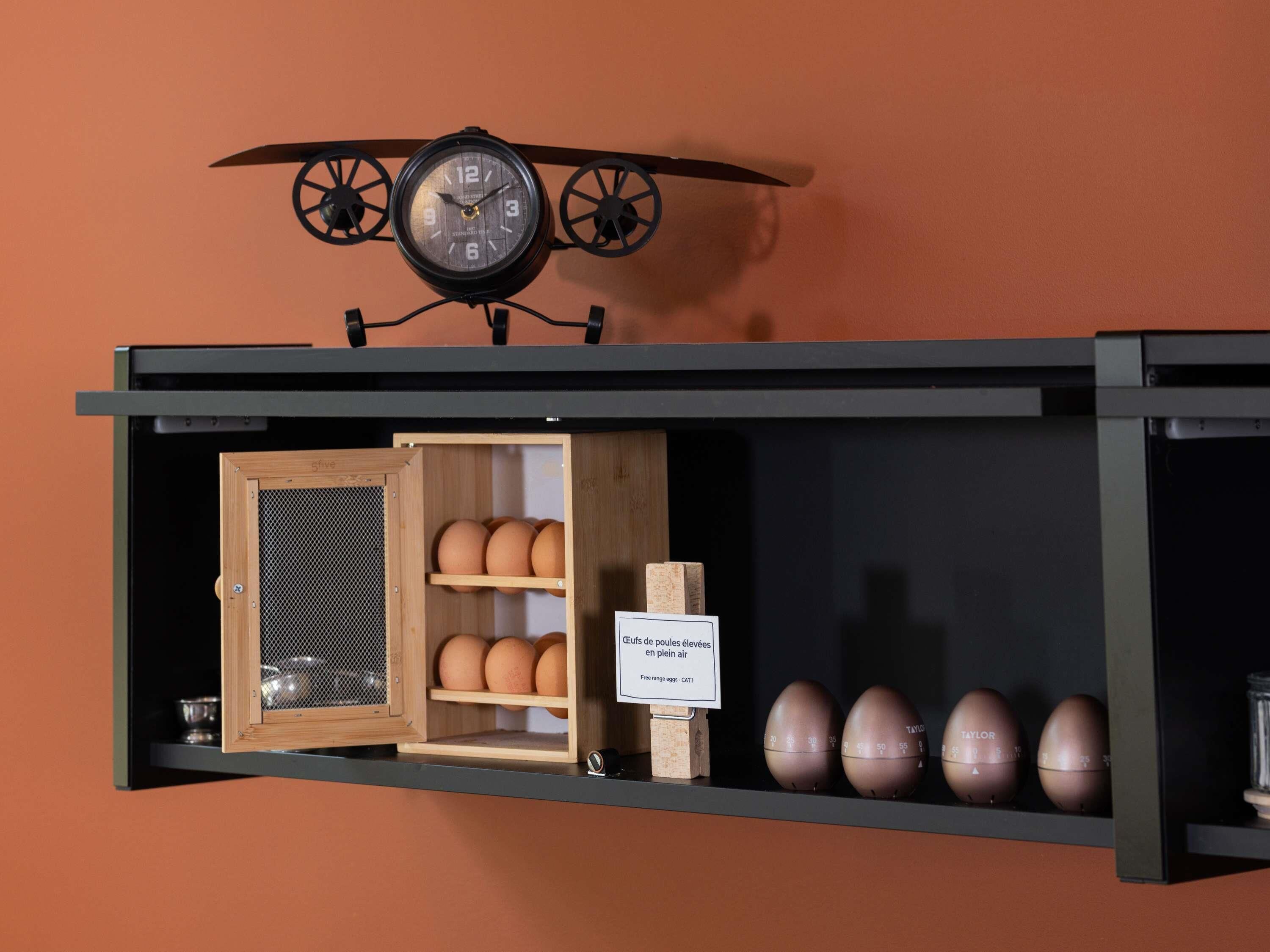 A shelf with a clock, eggs, and a sign.