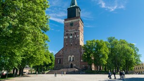 A historic church with a tall tower and a clock, surrounded by trees and open space. - Omena Hotel Turku Humalistonkatu (Turku)