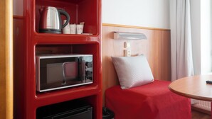 A compact hotel room with a red minibar, a microwave, a kettle, and a small table with a remote control. - Omena Hotel Turku Humalistonkatu (Turku)