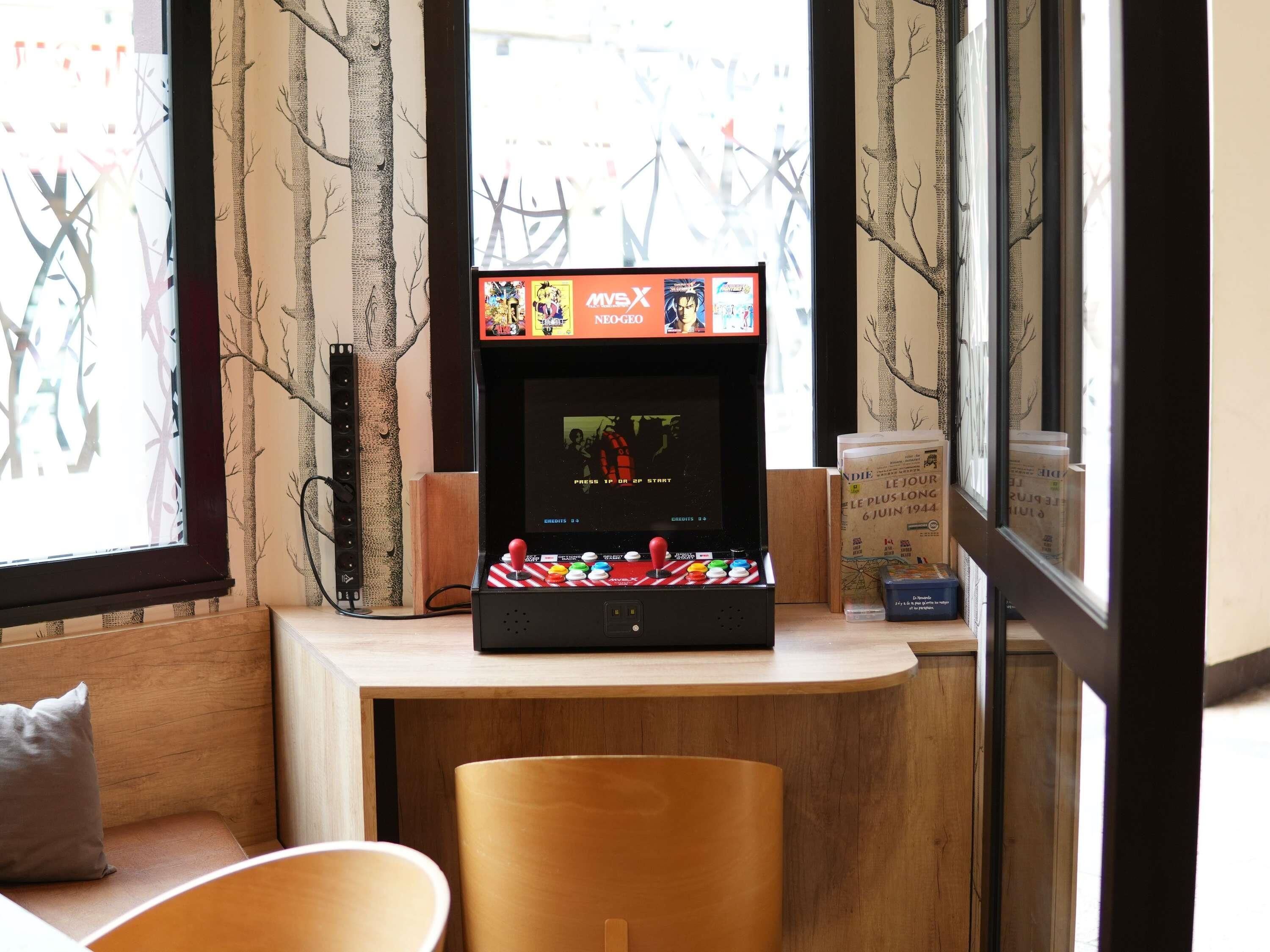 Una máquina de videojuegos retro en un rincón con vista al exterior.