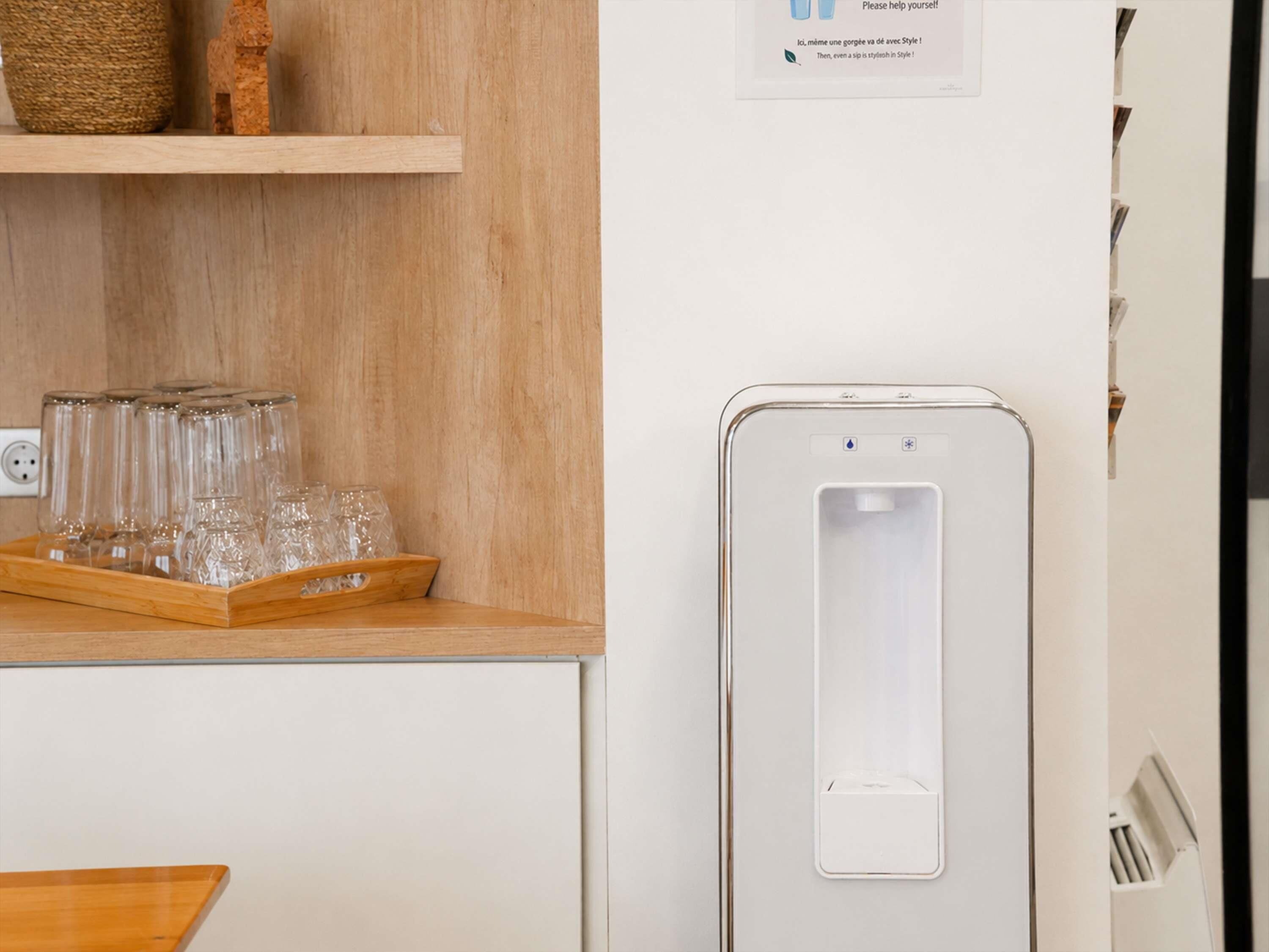 A kitchen area with a wooden countertop, a water dispenser, and a tray of glasses.