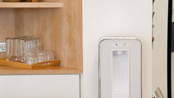 A kitchen area with a wooden countertop, a water dispenser, and a tray of glasses.