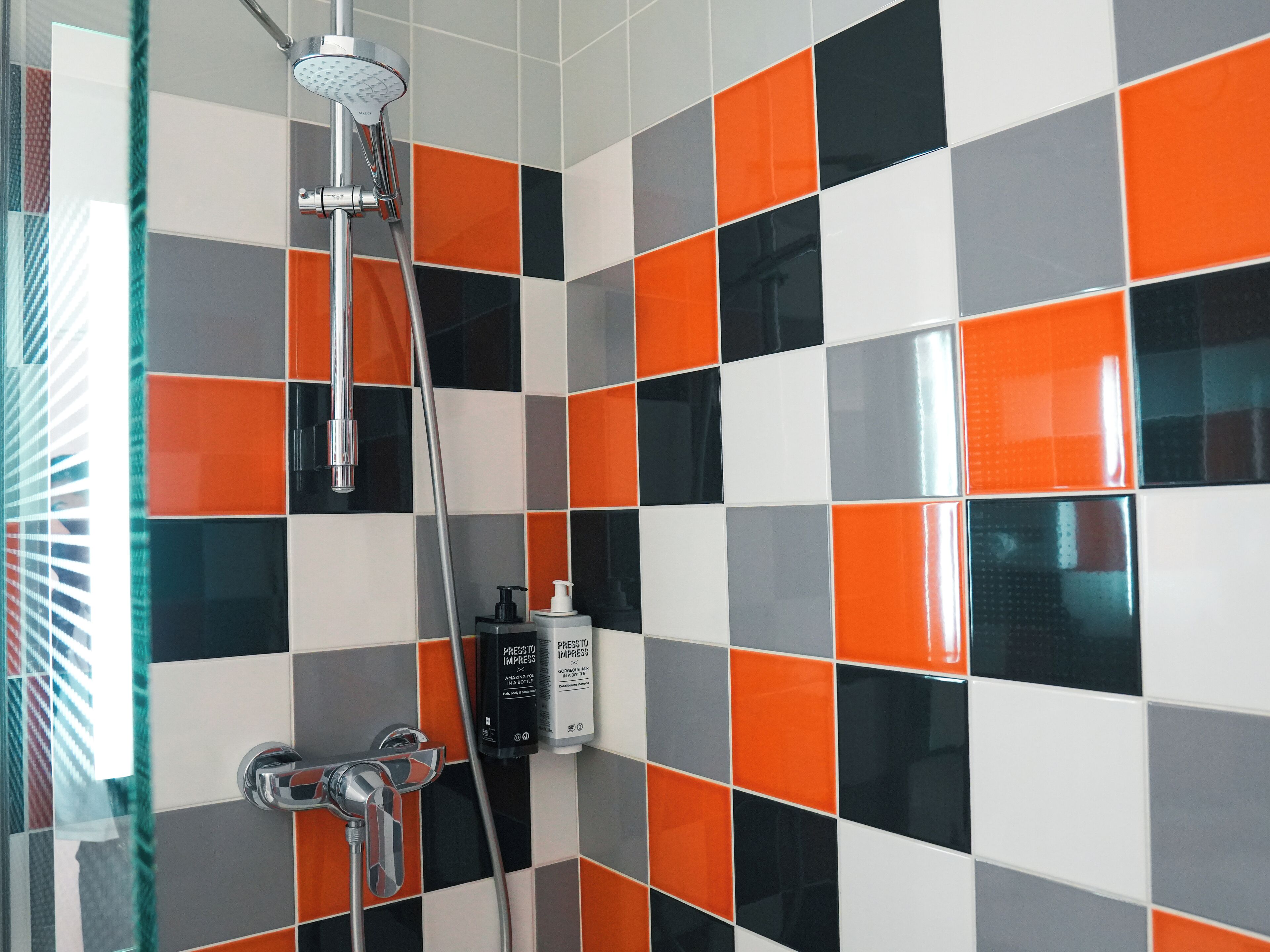 Ein Badezimmer mit Dusche, Glastür und Fliesenwand mit Schachbrettmuster.