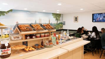 Zona de buffet con diferentes alimentos, un tarro de Nutella y un mural con vistas a la ciudad.