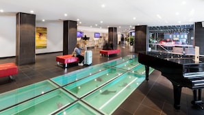 Un hall d’entrée avec une piscine à débordement, un piano à queue et des espaces de détente.