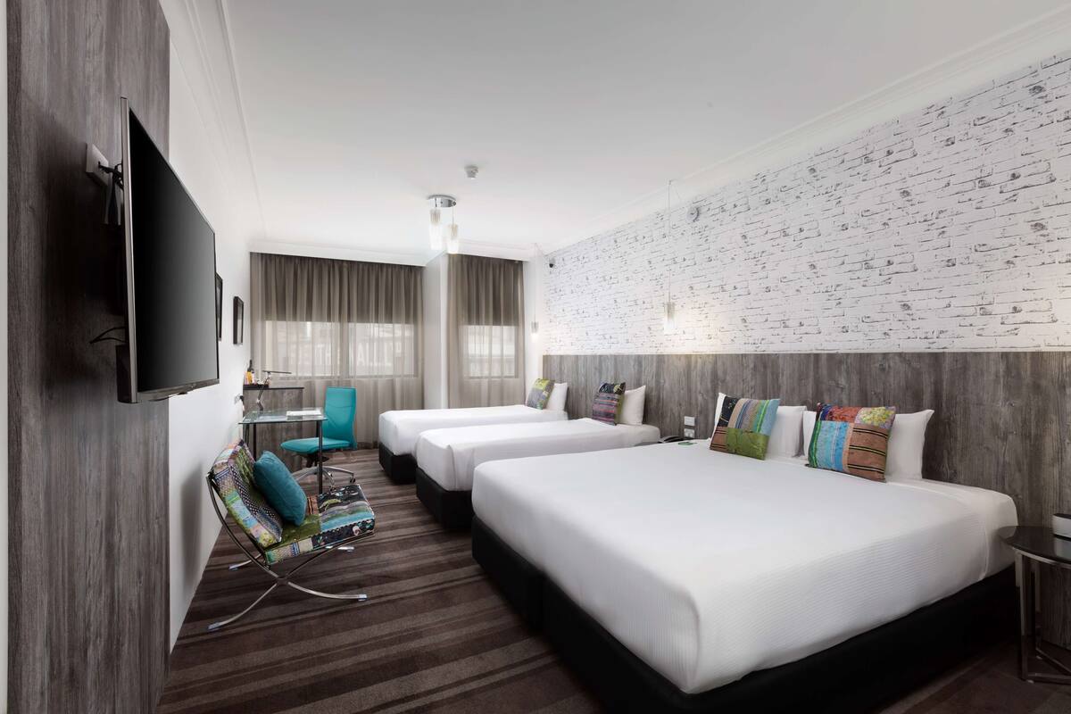 A hotel room with two beds, a TV, a desk, and a chair.