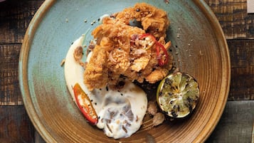 A plate of fried chicken with sauce and a lime wedge on a rustic wooden table.