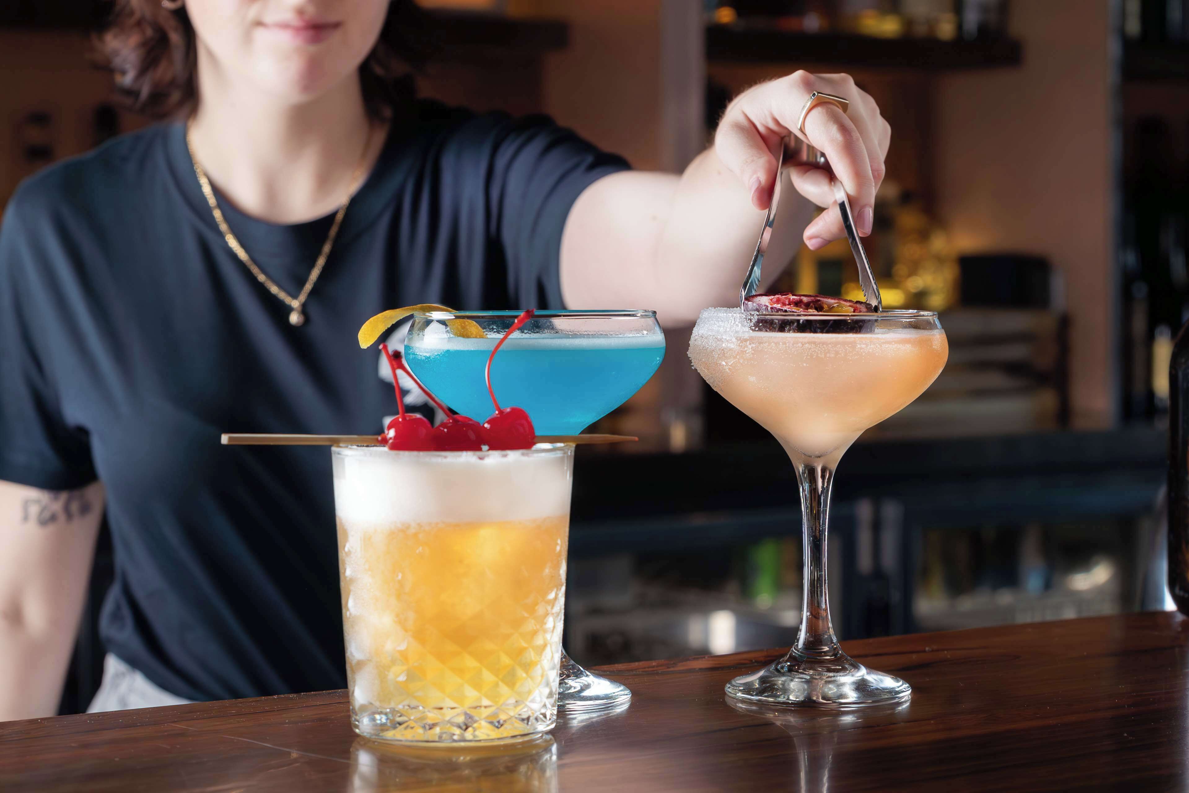 A person at a bar with two drinks in front of them.