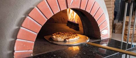 A pizza oven with a brick arch and a pizza inside.