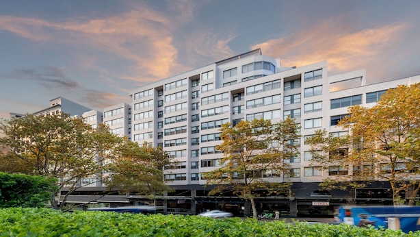 Un immeuble moderne à plusieurs étages, doté d’un toit plat et de grandes fenêtres.