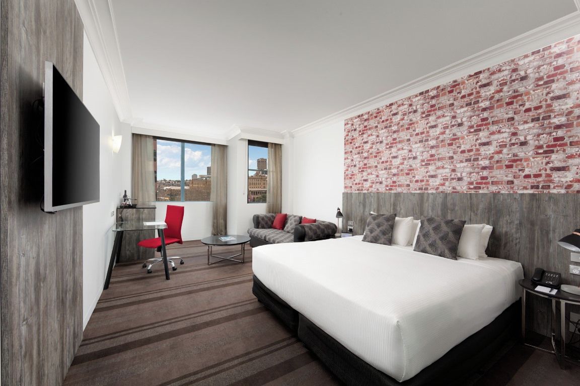 Una habitación de hotel con una cama grande, un escritorio, una silla y un televisor.