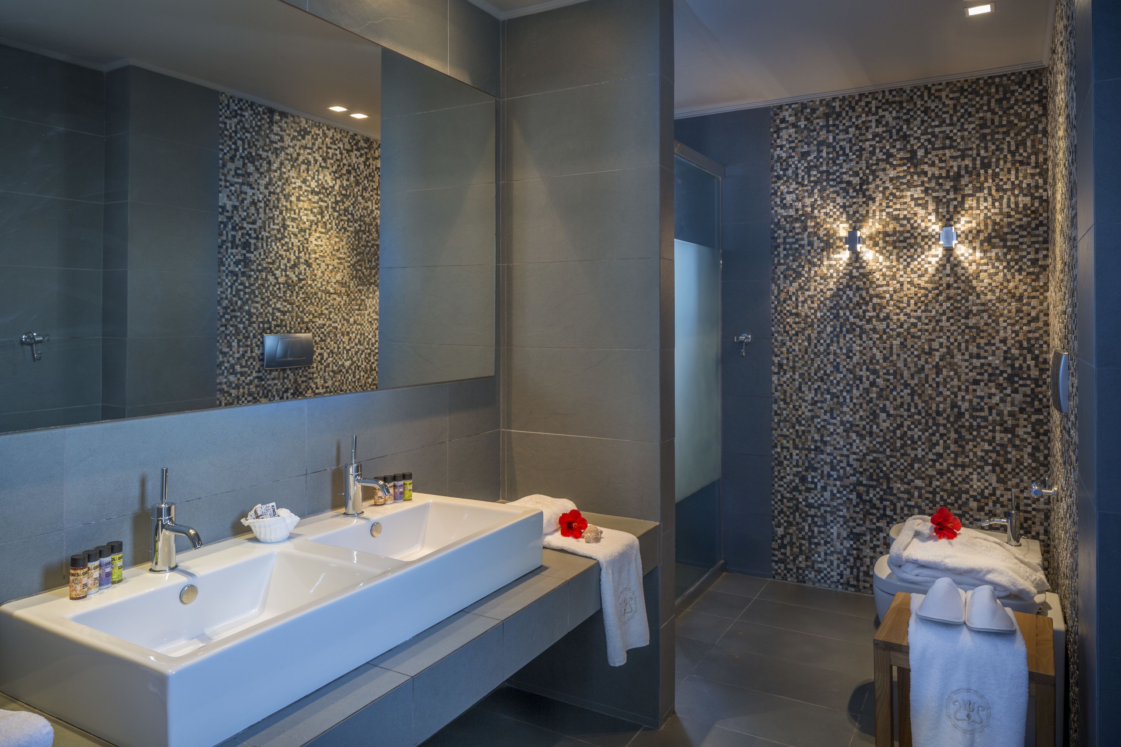 Une salle de bain moderne avec deux lavabos, un grand miroir et un mur à texture.