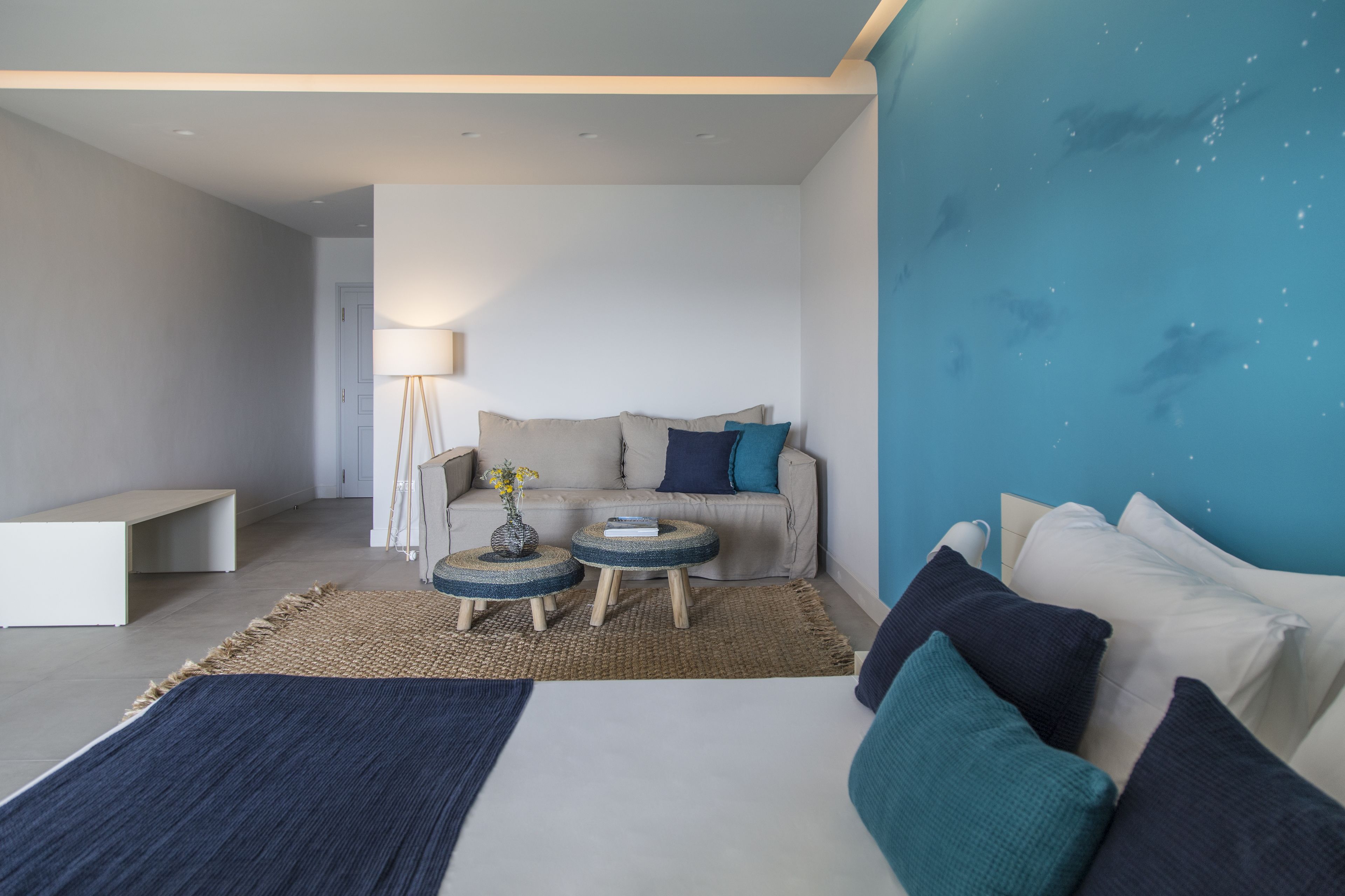 A modern bedroom with a bed, bedside tables, a sofa, and a lamp.