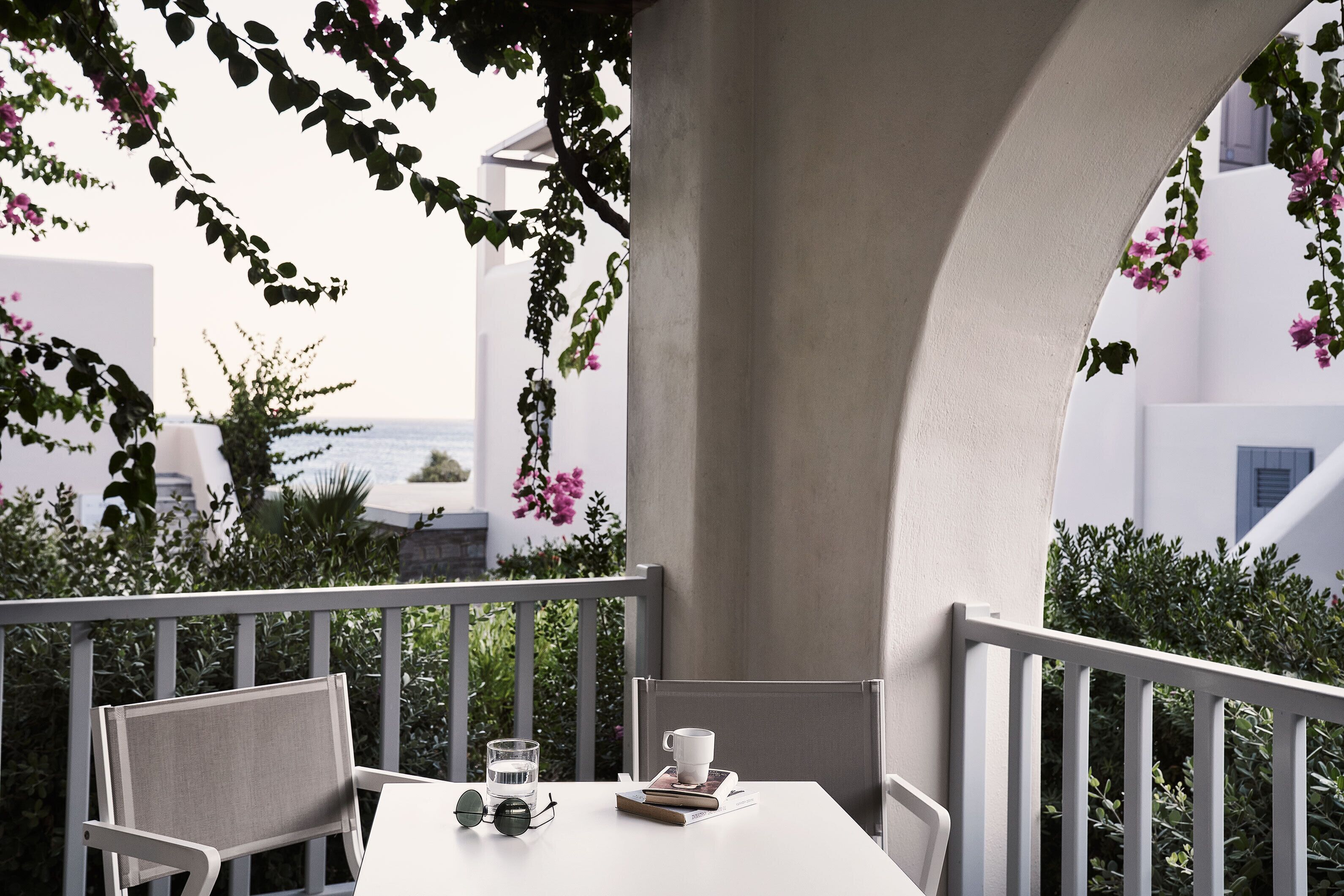 A balcony with a table, chairs, a cup, and a book.