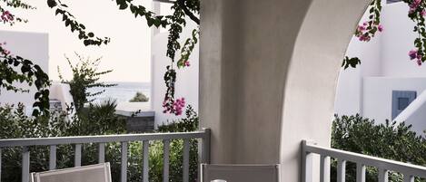 A balcony with a table, chairs, a cup, and a book.