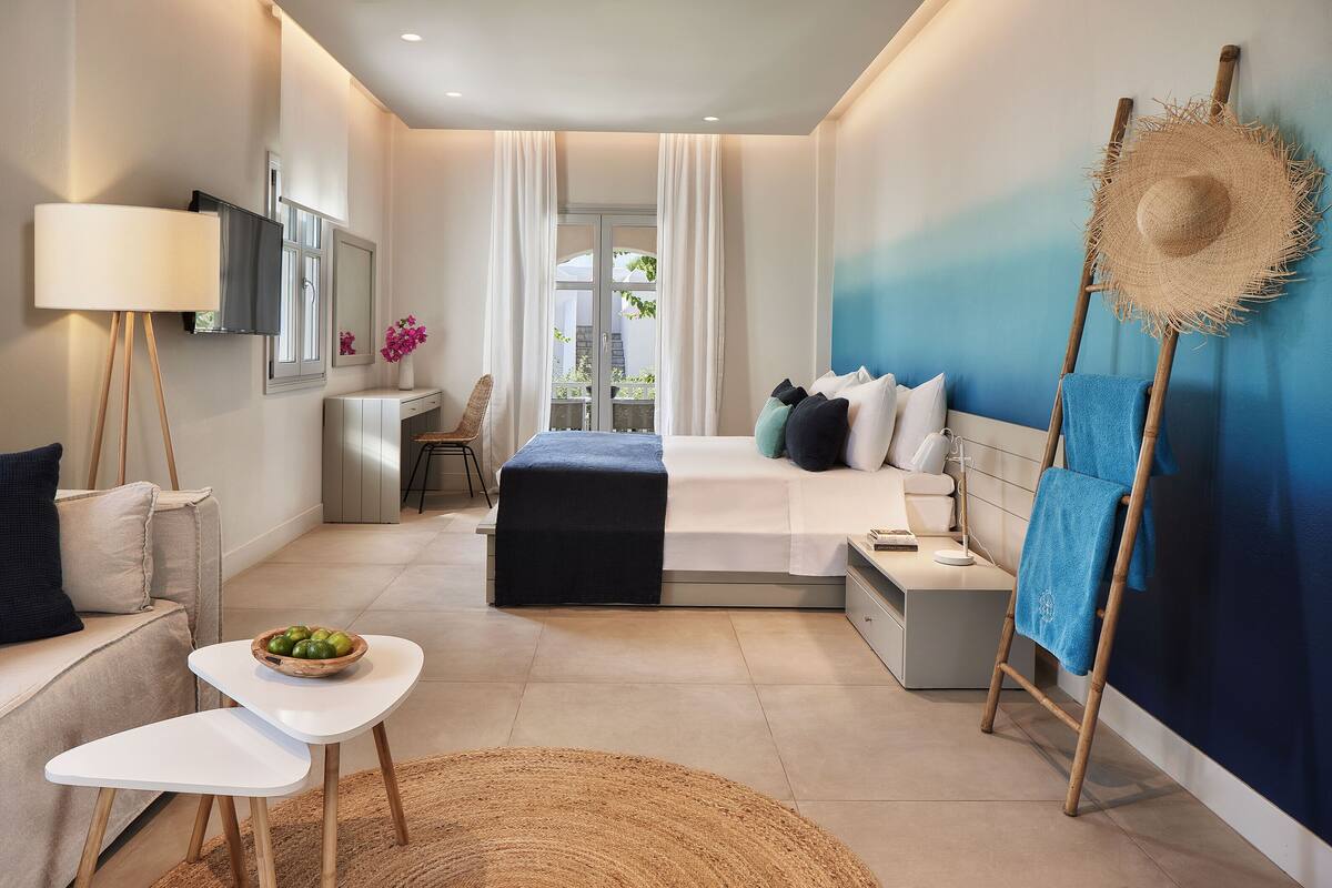 Ein modernes Schlafzimmer mit Bett, Nachttisch, Lampe und Blick ins Freie.