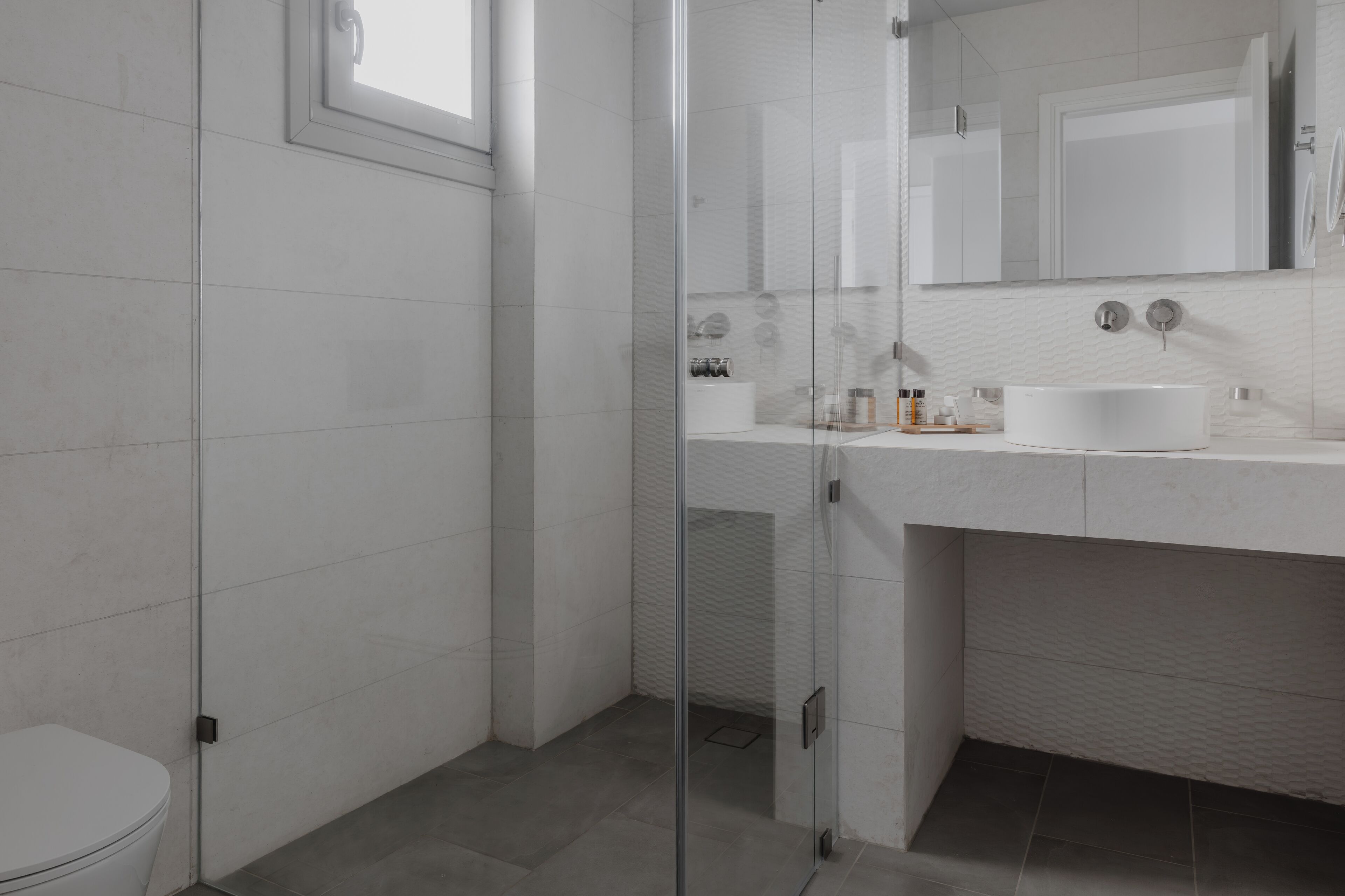 A modern bathroom with a glass shower enclosure, a white sink, and a toilet.