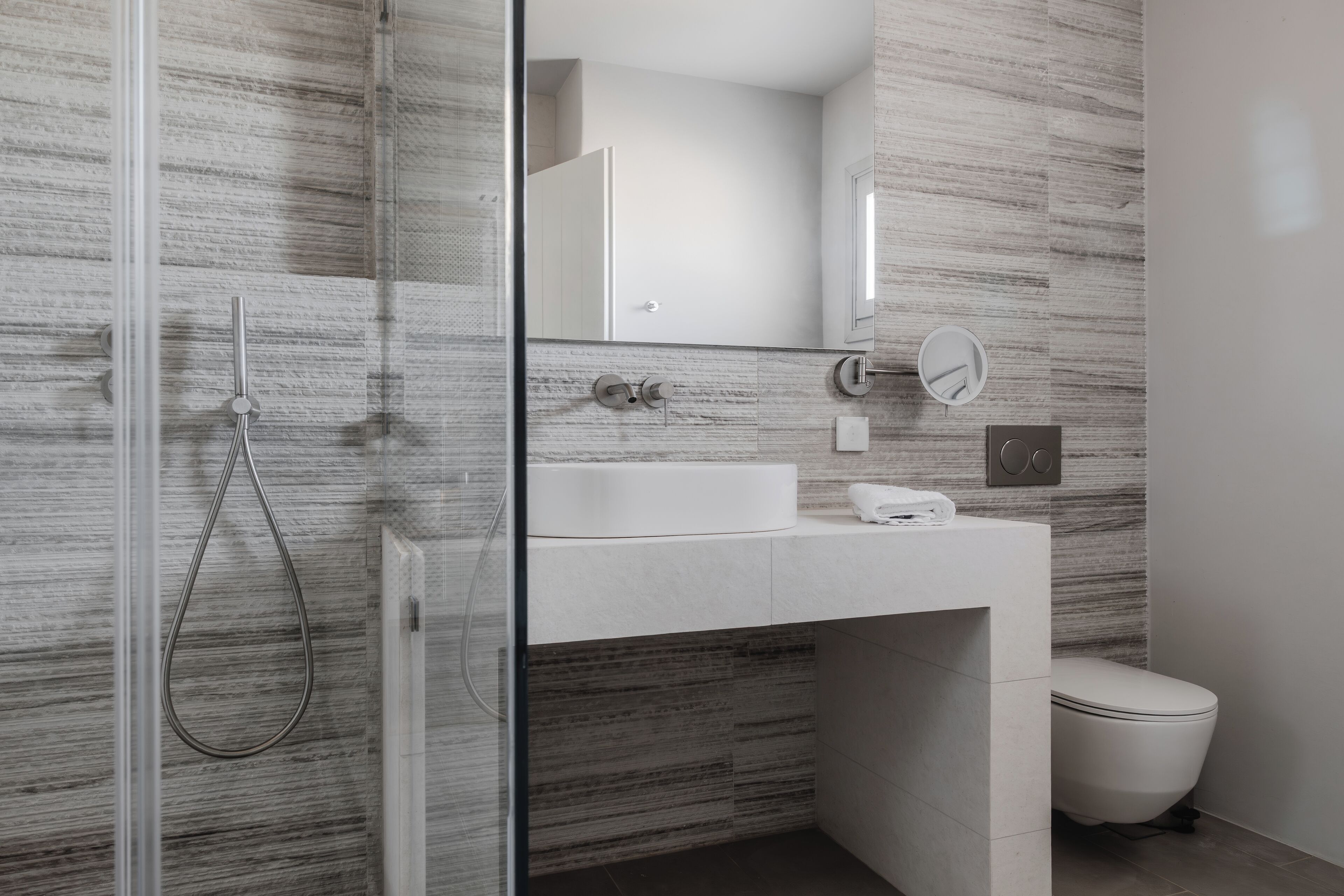 A modern bathroom with a glass shower enclosure, a white sink, and a toilet.