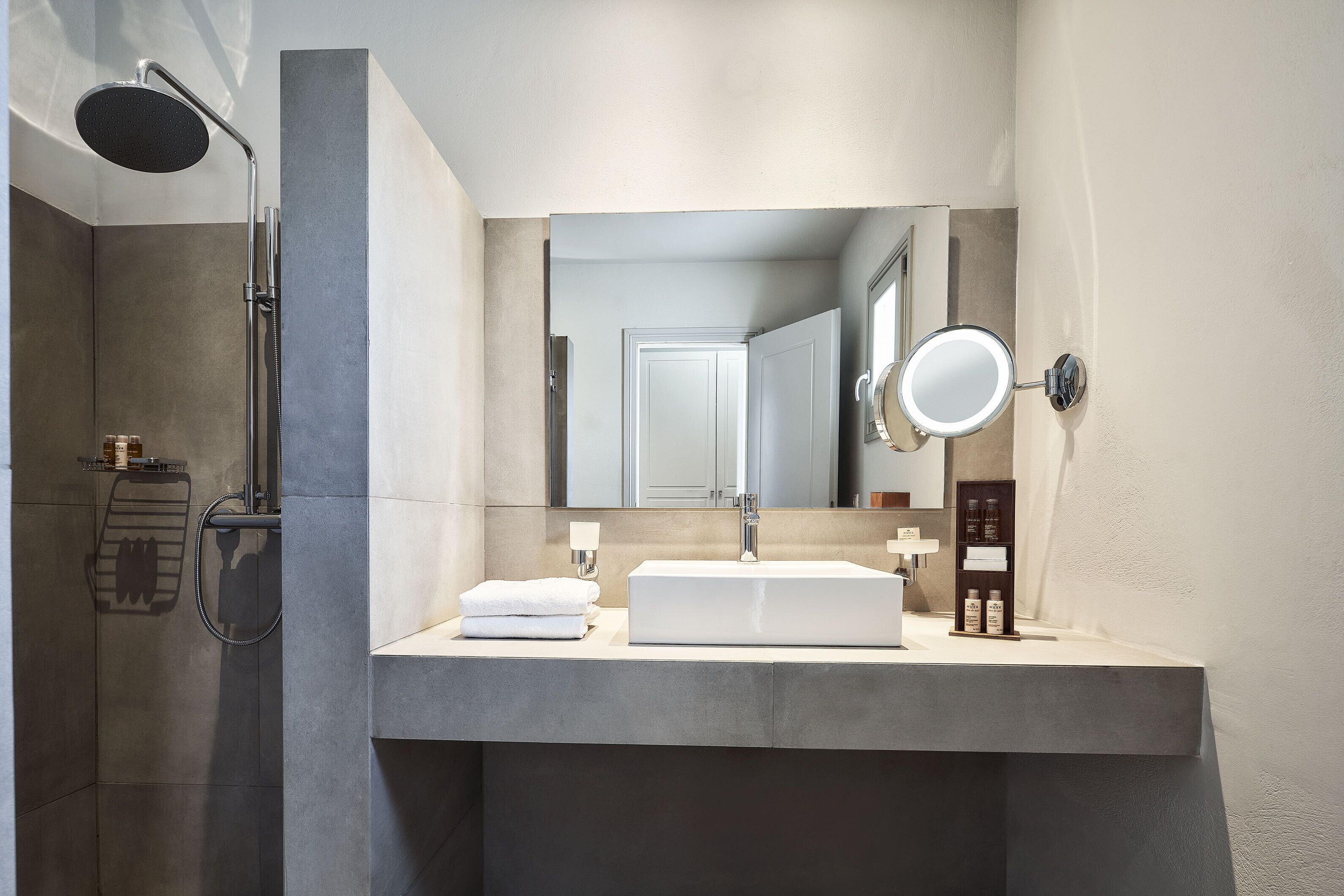 A modern bathroom with a large mirror, a built-in sink, and a shower.