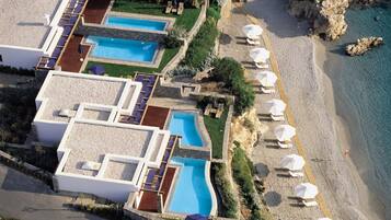 Un resort con varias piscinas, una playa con sombrillas y un litoral rocoso.
