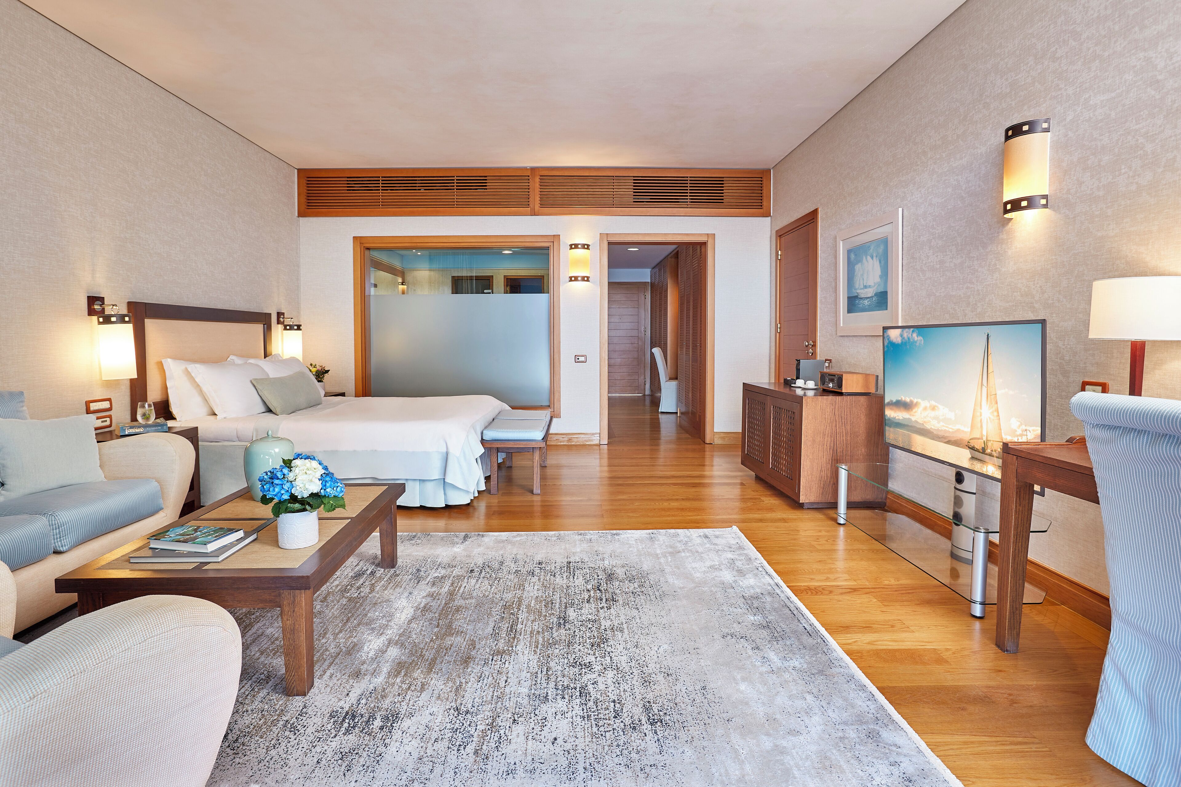 Una habitación de hotel con cama, sofá, mesa de centro y televisión.