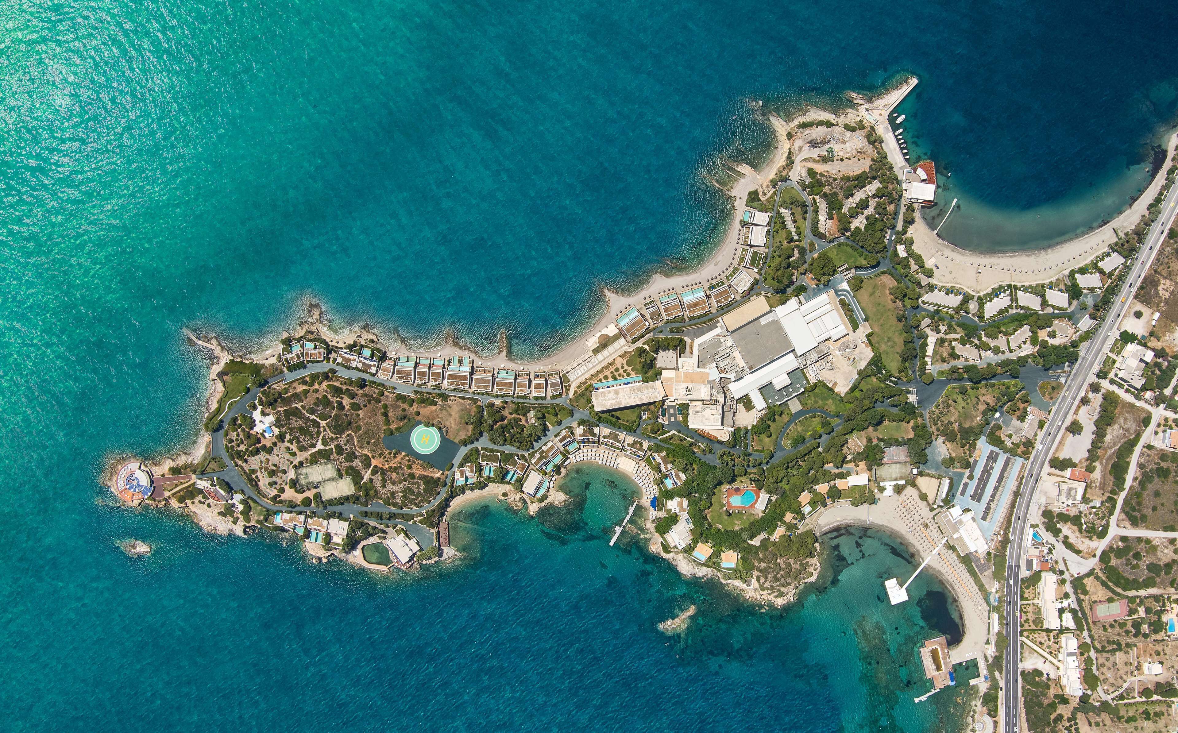 An aerial view of a coastal resort with multiple buildings, a marina, and a beach.