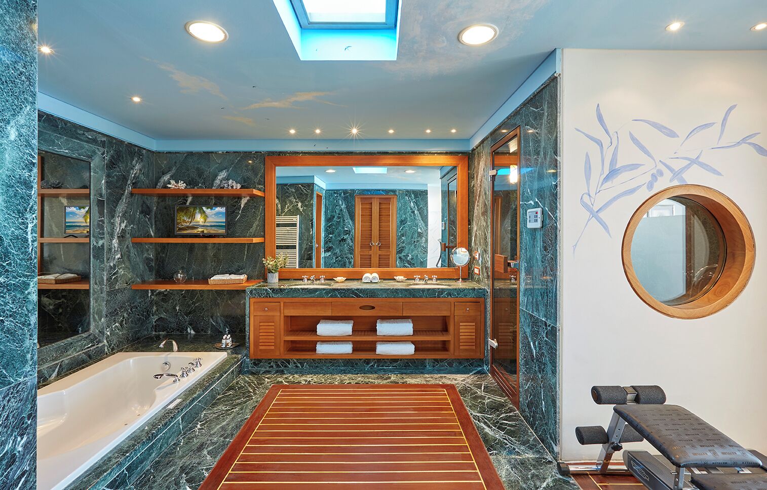 Un baño lujoso con tocador de mármol, un espejo grande, una bañera y una banca de gimnasio.