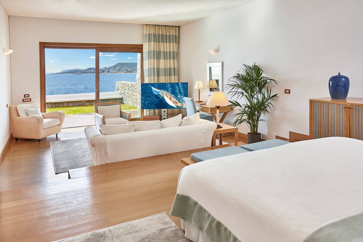 Ein modernes Hotelzimmer mit einem großen Bett, einer Sitzecke, einem Schreibtisch und Meerblick.