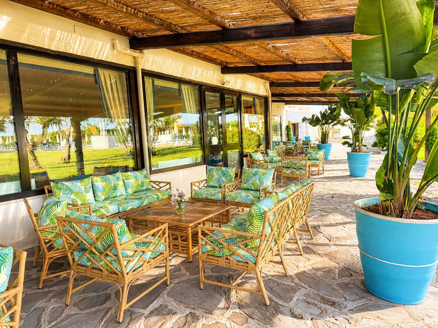An outdoor seating area with wicker furniture and large windows.
