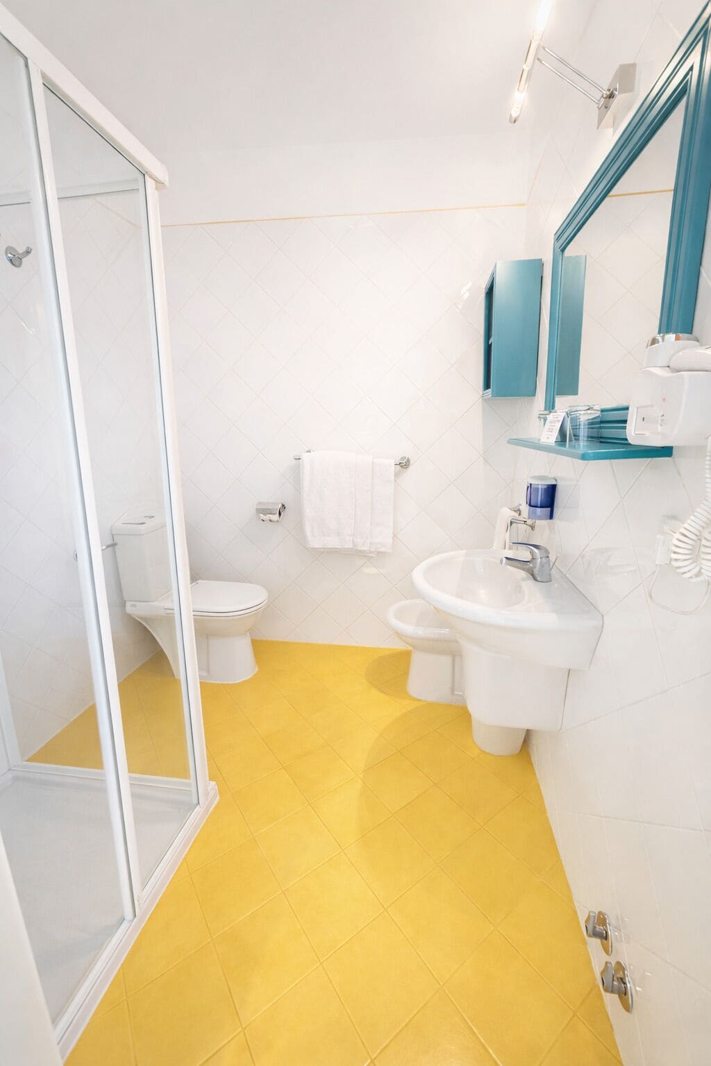 A bathroom with a glass shower enclosure, a toilet, a sink, and a mirror.