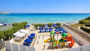 A beach with clear blue waters, sun loungers, umbrellas, and a playground. - Hotel Del Levante (Fasano)