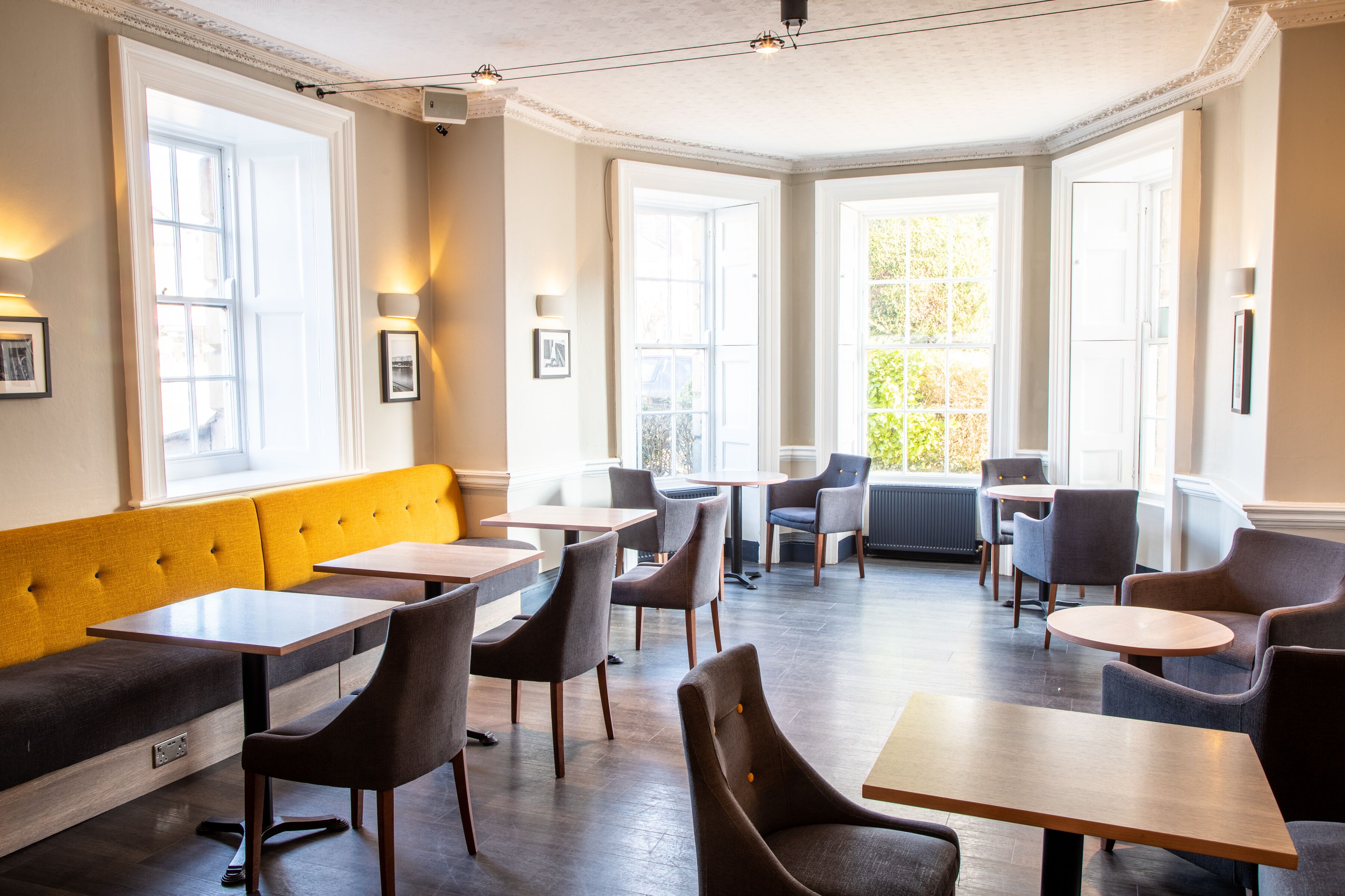 A dining area with a yellow bench, multiple tables, and chairs.