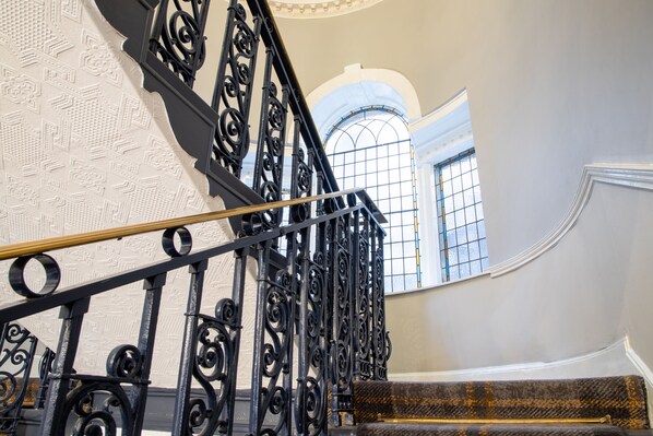 Una imponente escalera con barandillas de metal negro ornamentado y un revestimiento de pared con diseño.