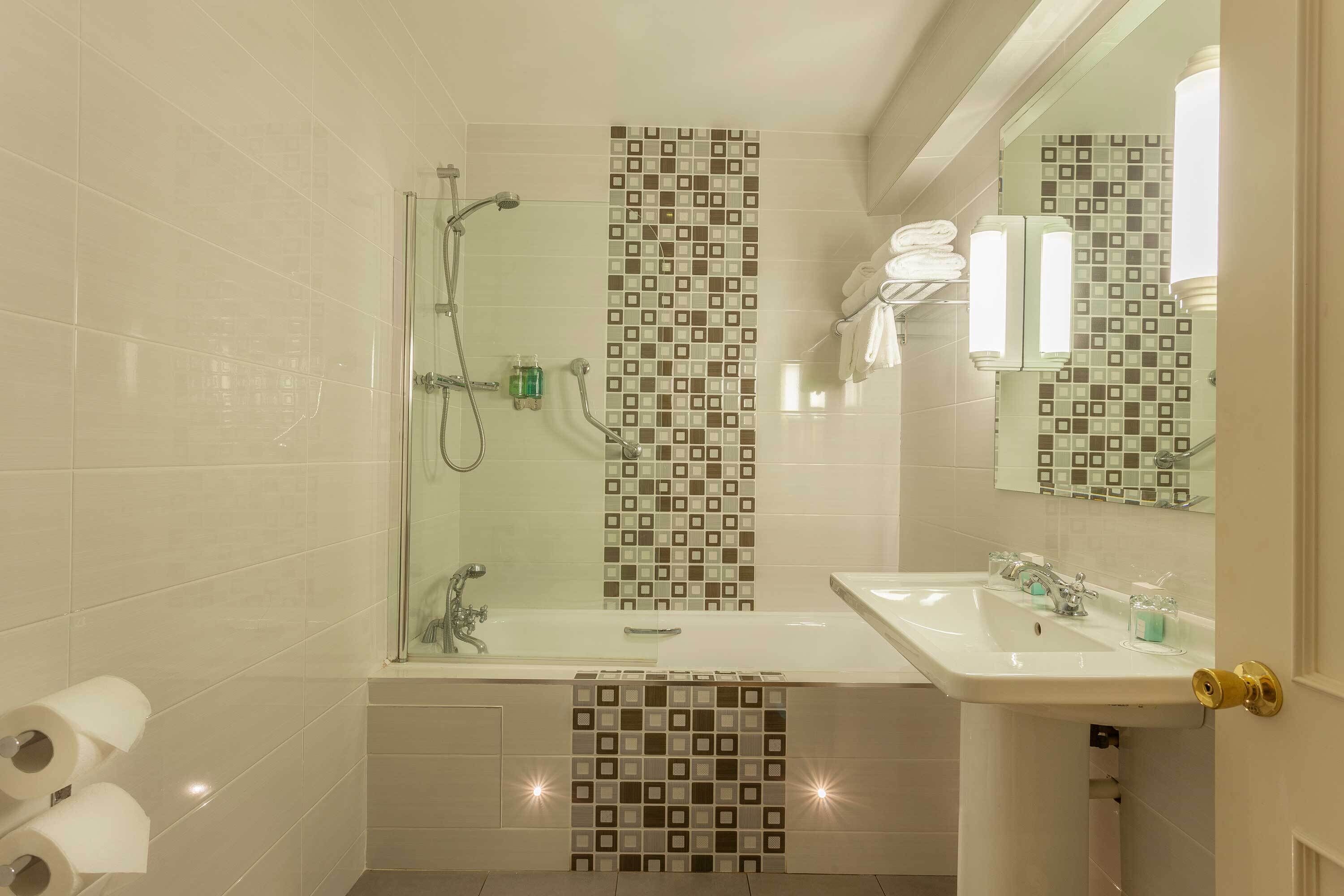 Un baño moderno con ducha de vidrio, un lavabo grande y un espejo sobre el lavabo.
