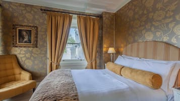 Ein Hotelzimmer mit Bett, Stuhl, Lampe und einem Fenster mit Vorhängen.