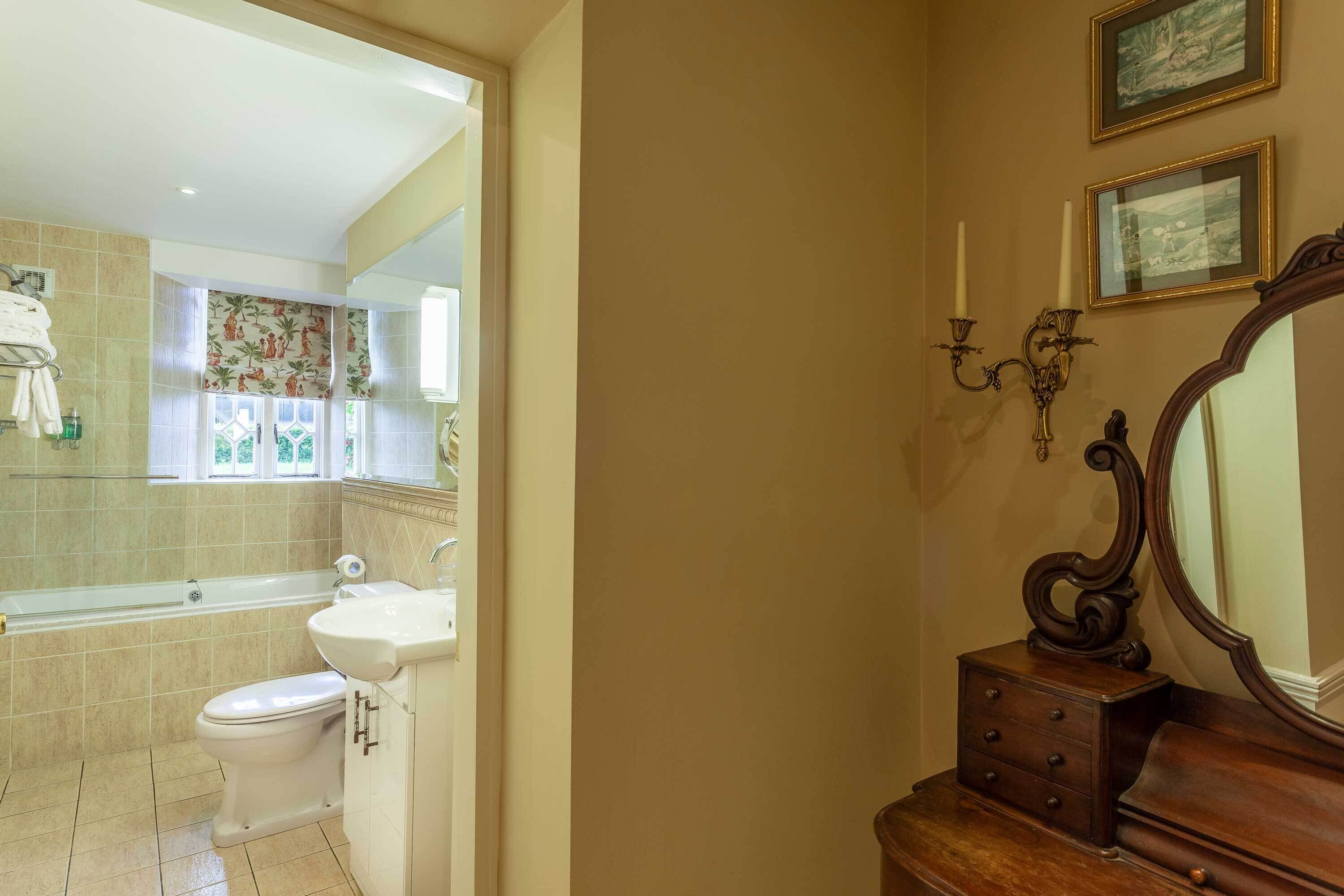 A bathroom with a bathtub, toilet, sink, and a vanity with a mirror.
