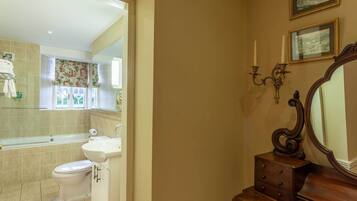 A bathroom with a bathtub, toilet, sink, and a vanity with a mirror.