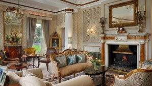 Une chambre luxueuse avec une cheminée, des meubles richement décorés et un grand miroir.