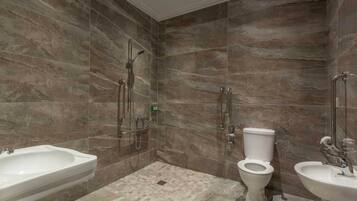 Een moderne badkamer met een douche, toilet en twee wasbakken.