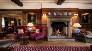 A traditional room with a fireplace, two armchairs, a sofa, and a patterned rug. - Buckland Manor (Broadway)