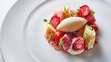 A dessert on a white plate with strawberries, mint, and a scoop of ice cream.