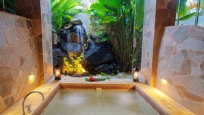 Un espace de bien-être agrémenté d’un mur en pierre, d’une petite cascade et d’un bain à remous.