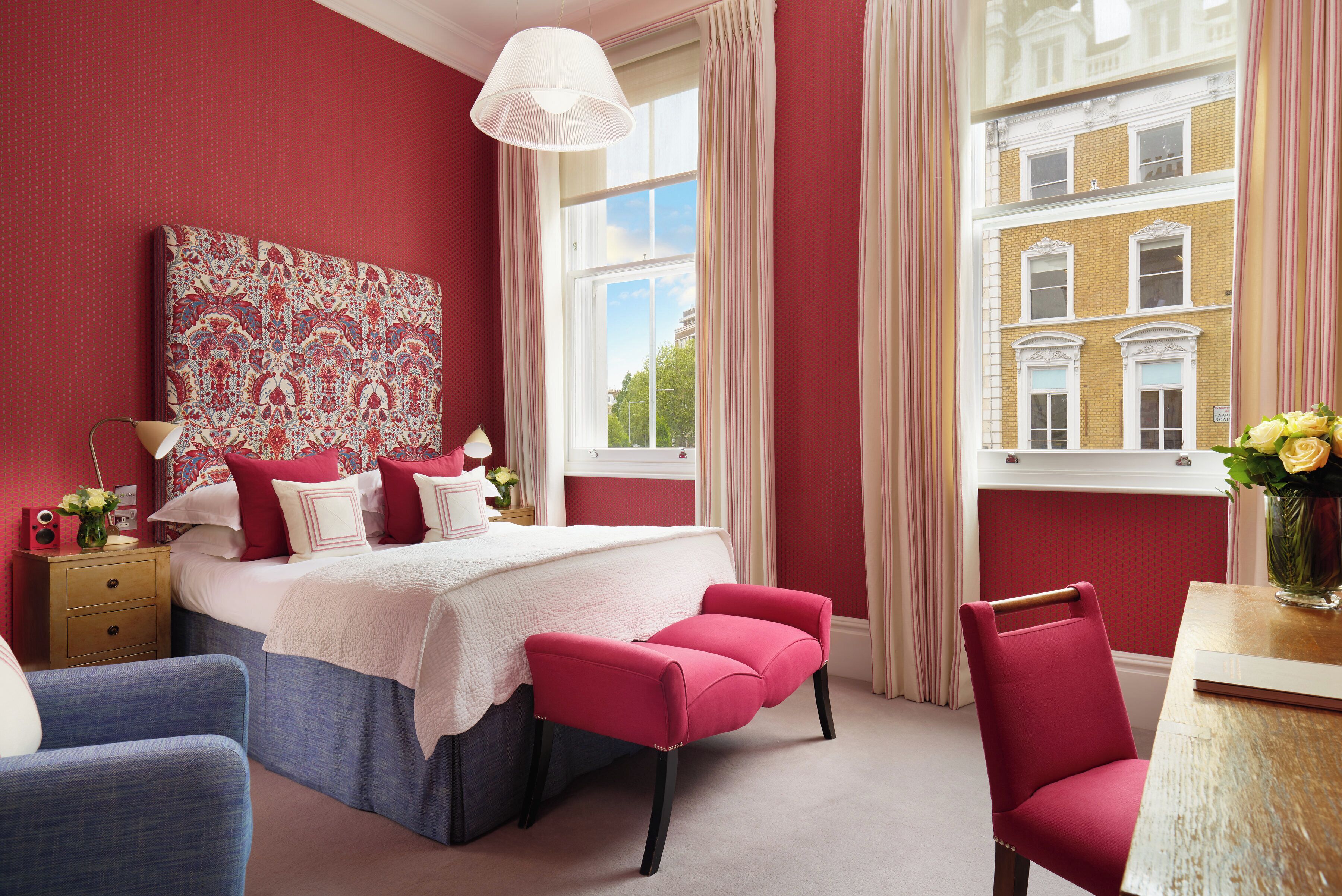 A bedroom with a large bed, a nightstand, a chair, and a window with curtains.