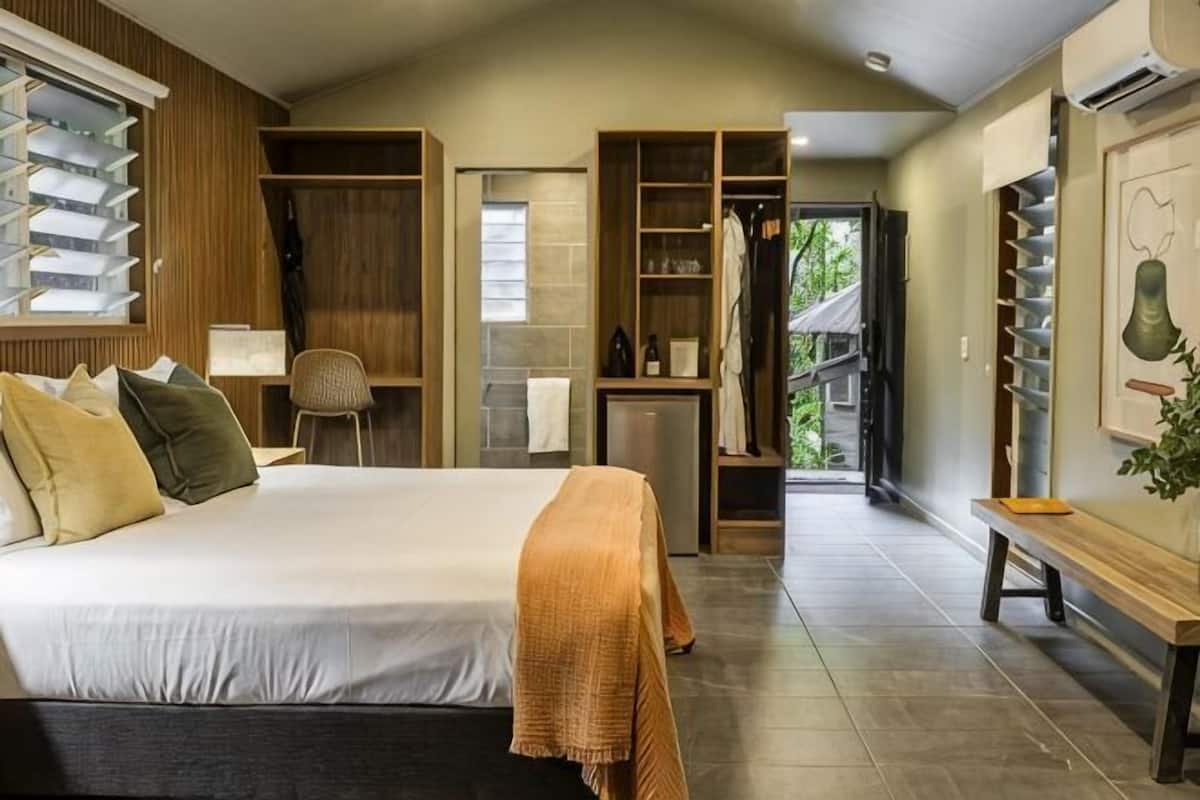 A bedroom with a bed, bedside tables, a wardrobe, a desk, and a chair.